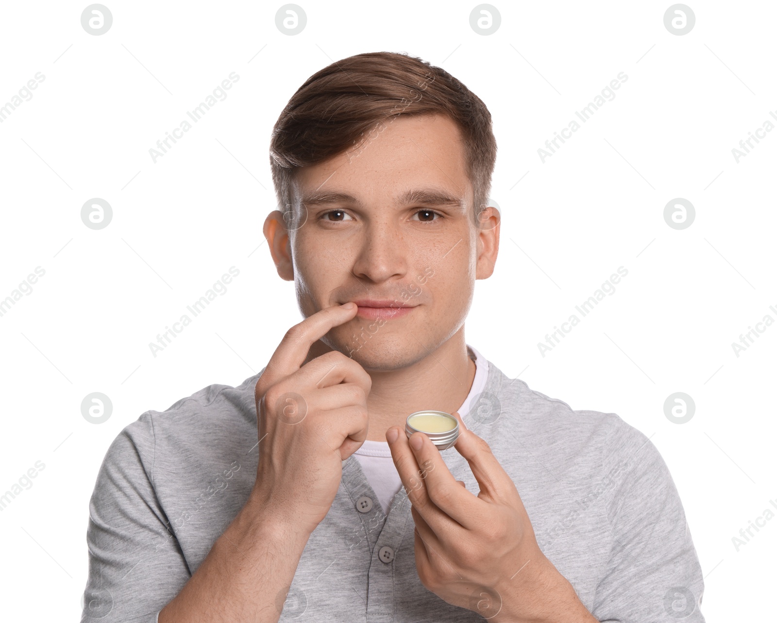 Young man applying lip balm onto his lips on white background Photo of Young man applying lip balm onto his lips on white background
