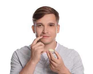 Photo of Young man applying lip balm onto his lips on white background