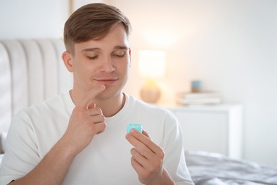 Photo of Young man applying lip balm onto his lips at home