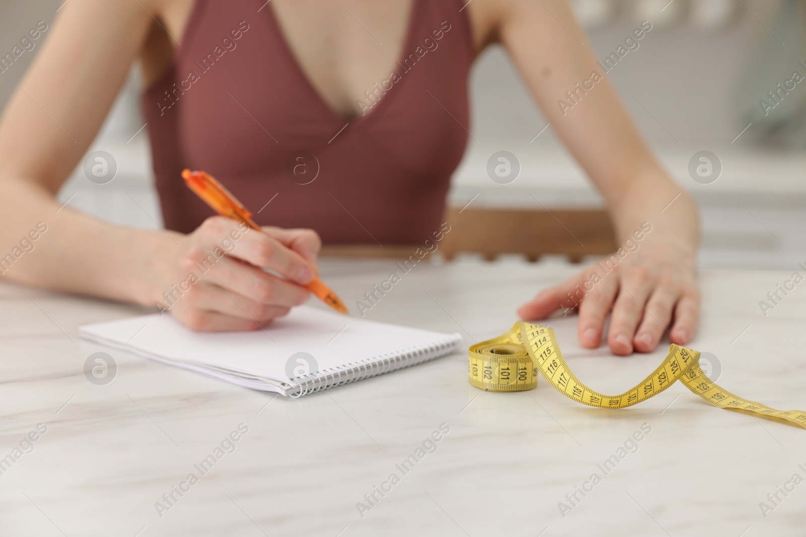 Woman developing diet plan at white marble table indoors, closeup Photo of Woman developing diet plan at white marble table indoors, closeup