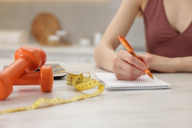 Photo of Woman developing diet plan at white marble table indoors, closeup