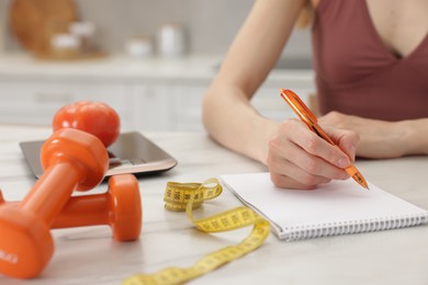 Photo of Woman developing diet plan at white marble table indoors, closeup