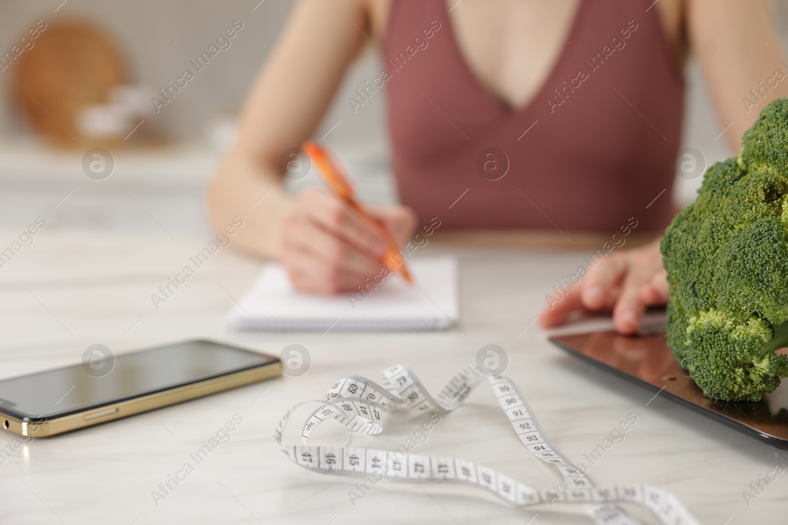 Woman developing diet plan at white marble table indoors, selective focus Photo of Woman developing diet plan at white marble table indoors, selective focus