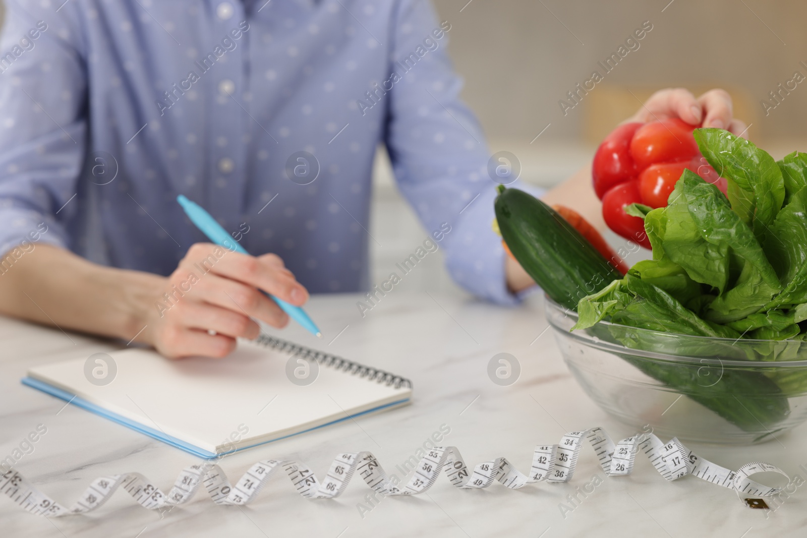Woman developing diet plan at white marble table indoors, closeup Photo of Woman developing diet plan at white marble table indoors, closeup