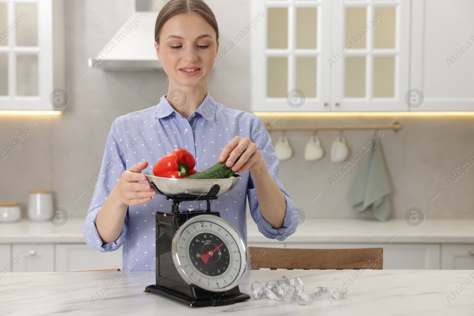 Woman weighting vegetables on kitchen scale at white marble table indoors, space for text Photo of Woman weighting vegetables on kitchen scale at white marble table indoors, space for text
