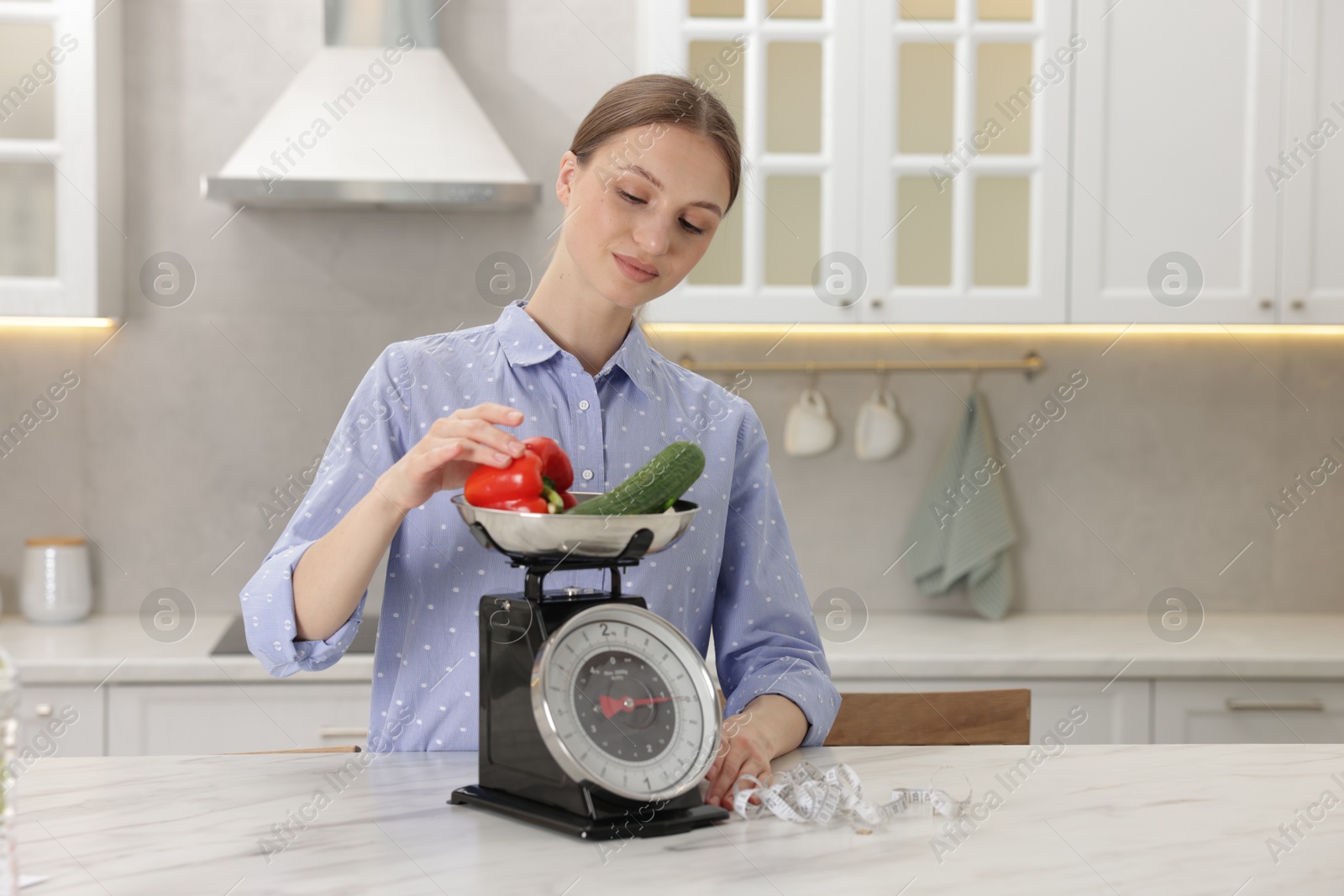Woman weighting vegetables on kitchen scale at white marble table indoors, space for text Photo of Woman weighting vegetables on kitchen scale at white marble table indoors, space for text