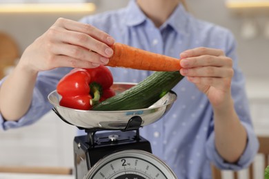 Photo of Woman weighting vegetables on kitchen scale indoors, closeup
