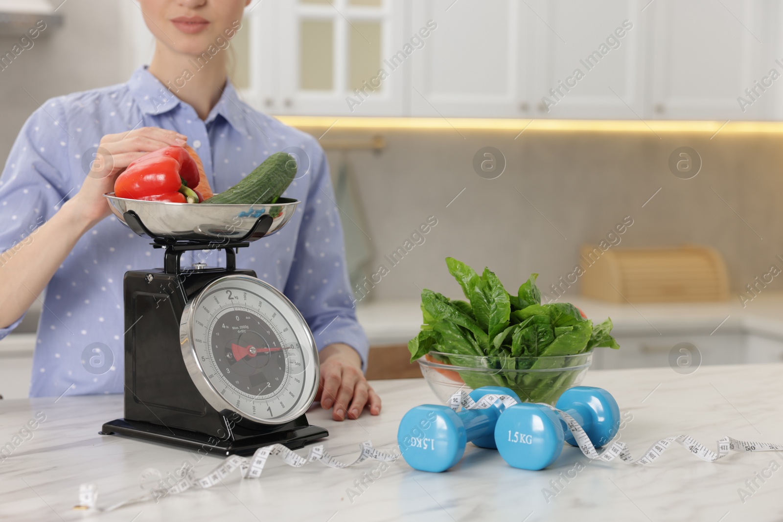 Woman weighting vegetables on kitchen scale at white marble table indoors, closeup Photo of Woman weighting vegetables on kitchen scale at white marble table indoors, closeup