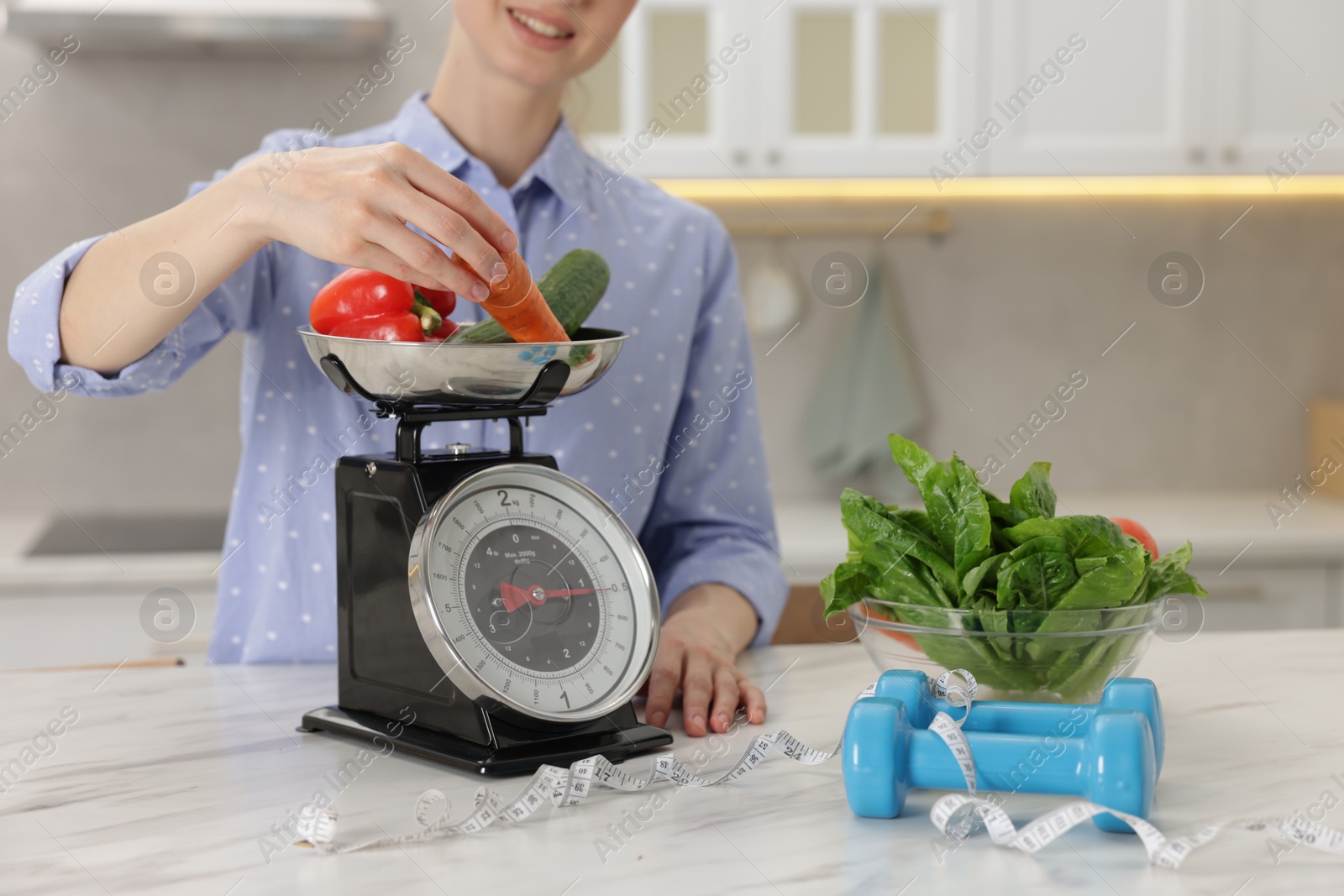 Woman weighting vegetables on kitchen scale at white marble table indoors, closeup Photo of Woman weighting vegetables on kitchen scale at white marble table indoors, closeup