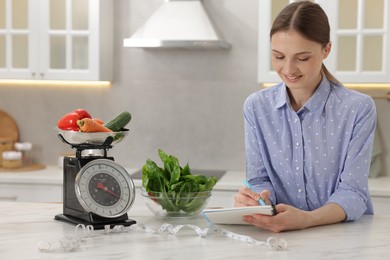 Photo of Woman developing diet plan at white marble table indoors