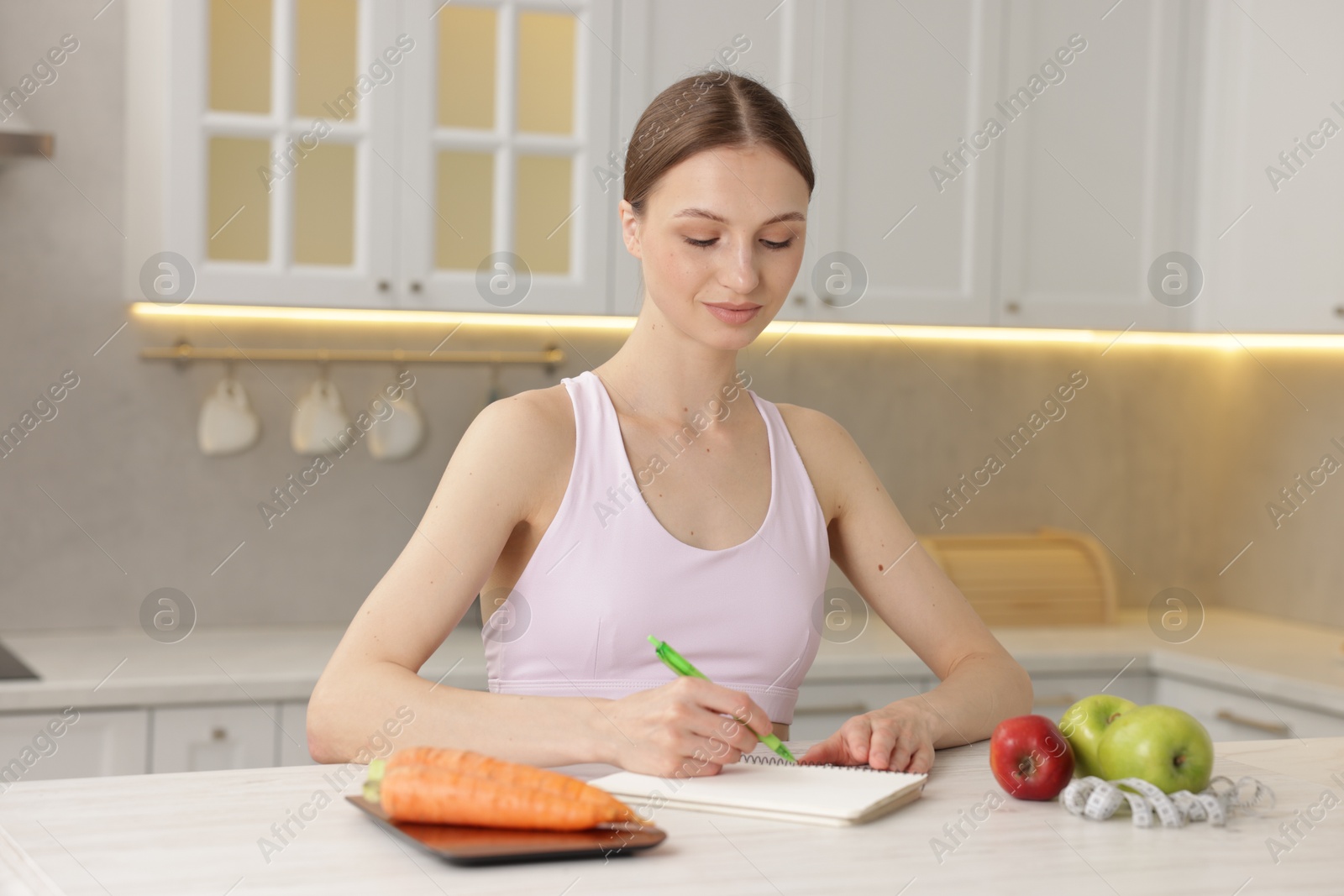 Woman developing diet plan at white wooden table indoors Photo of Woman developing diet plan at white wooden table indoors