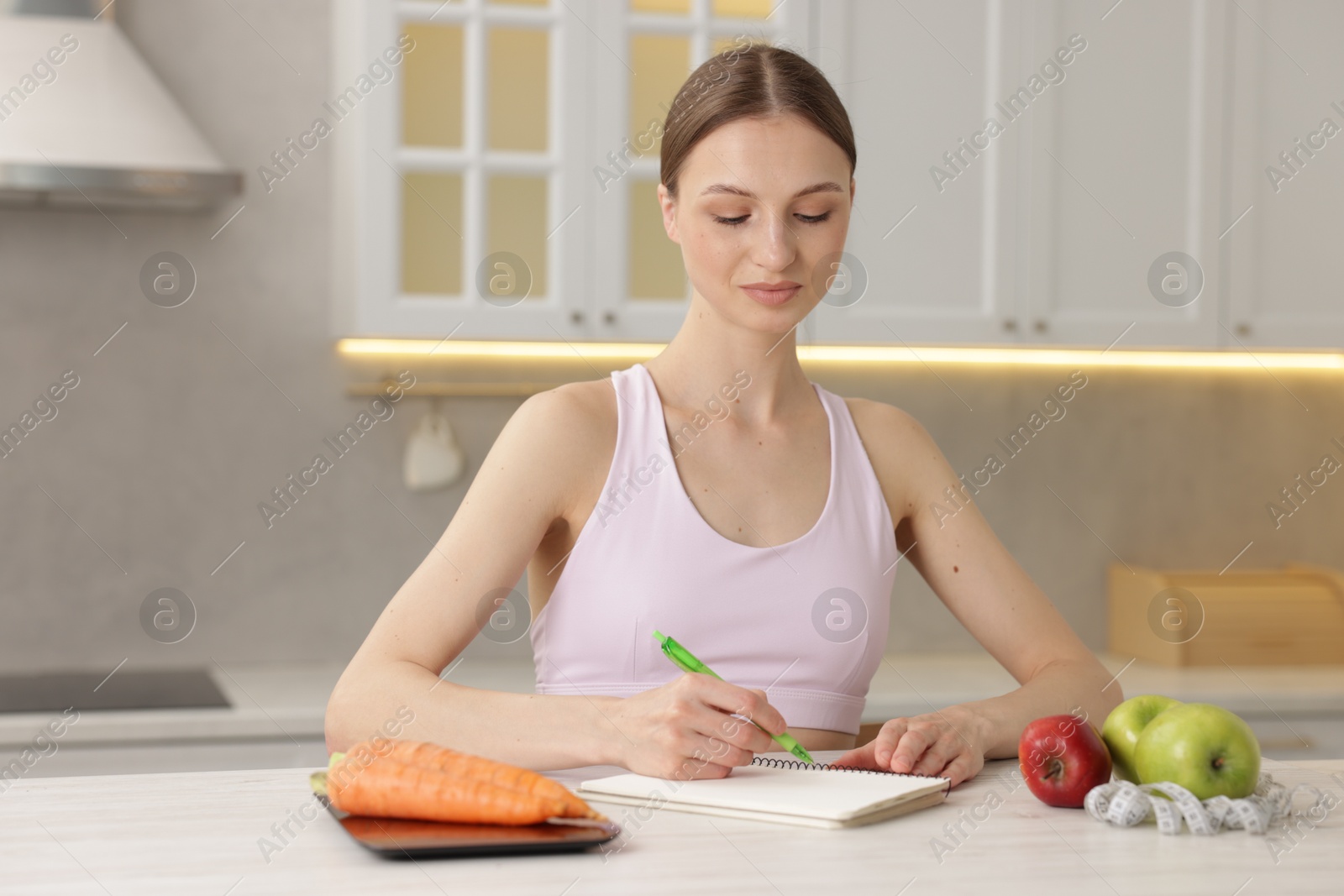 Woman developing diet plan at white wooden table indoors Photo of Woman developing diet plan at white wooden table indoors