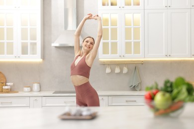 Photo of Slim woman in sportswear posing in kitchen, selective focus