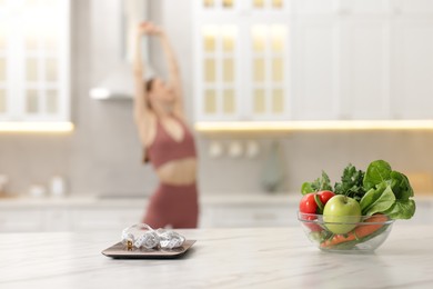 Photo of Slim woman in sportswear posing indoors, focus on kitchen scale, healthy food, and measuring tape