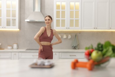 Photo of Slim woman in sportswear posing in kitchen, selective focus