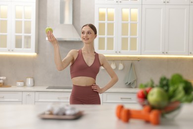 Photo of Slim woman with green apple in kitchen, selective focus