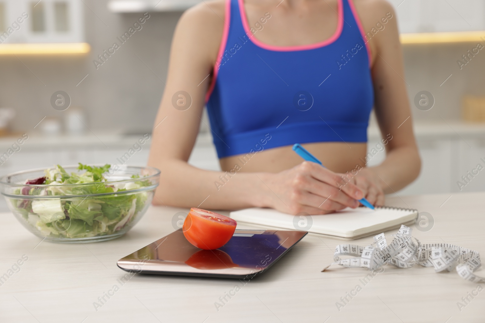 Photo of Woman developing diet plan at white table indoors, closeup