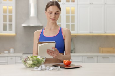 Photo of Woman developing diet plan at white table indoors