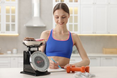 Photo of Woman developing diet plan at white table indoors