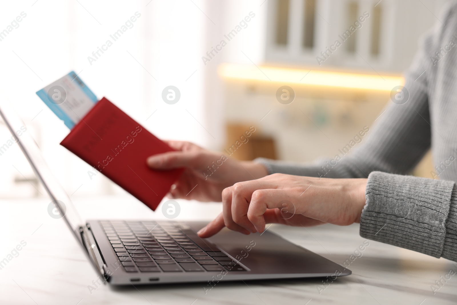 Woman with passport and flight ticket using laptop at white marble table indoors, closeup Photo of Woman with passport and flight ticket using laptop at white marble table indoors, closeup