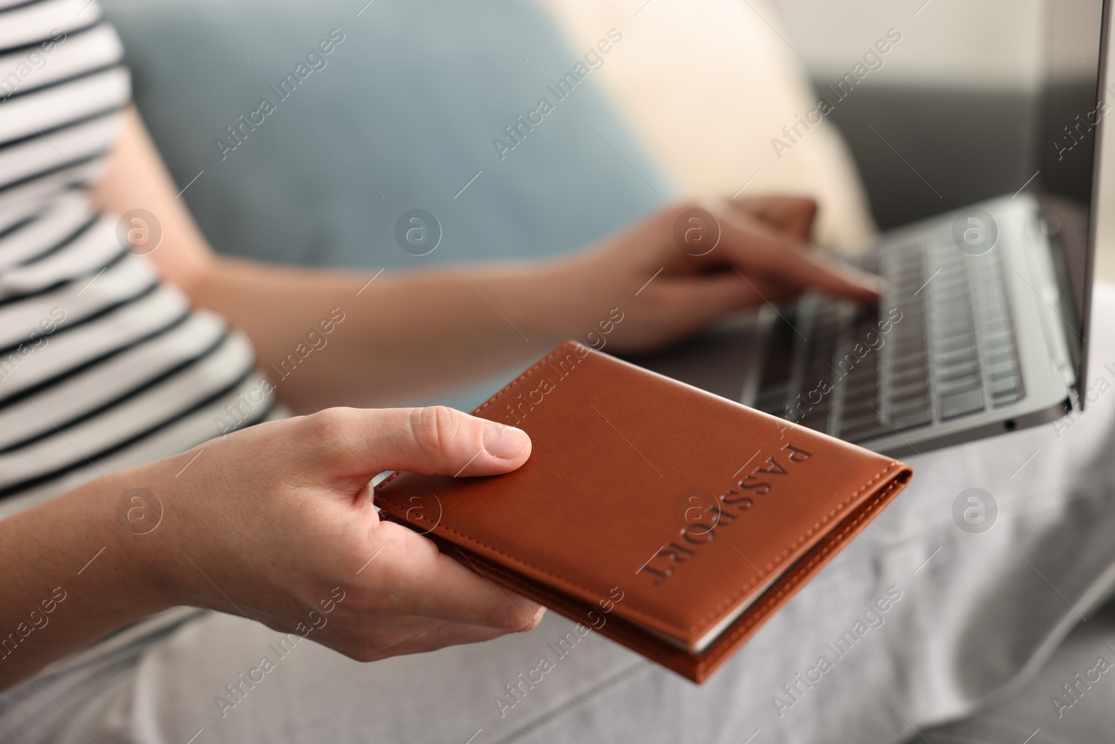 Woman with passport using laptop on sofa indoors, closeup Photo of Woman with passport using laptop on sofa indoors, closeup