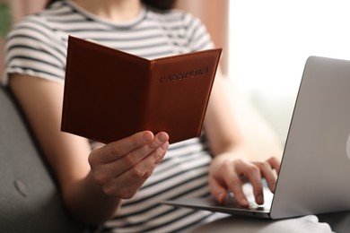 Photo of Woman with passport using laptop on sofa indoors, closeup