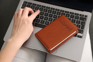 Photo of Woman with passport using laptop indoors, above view