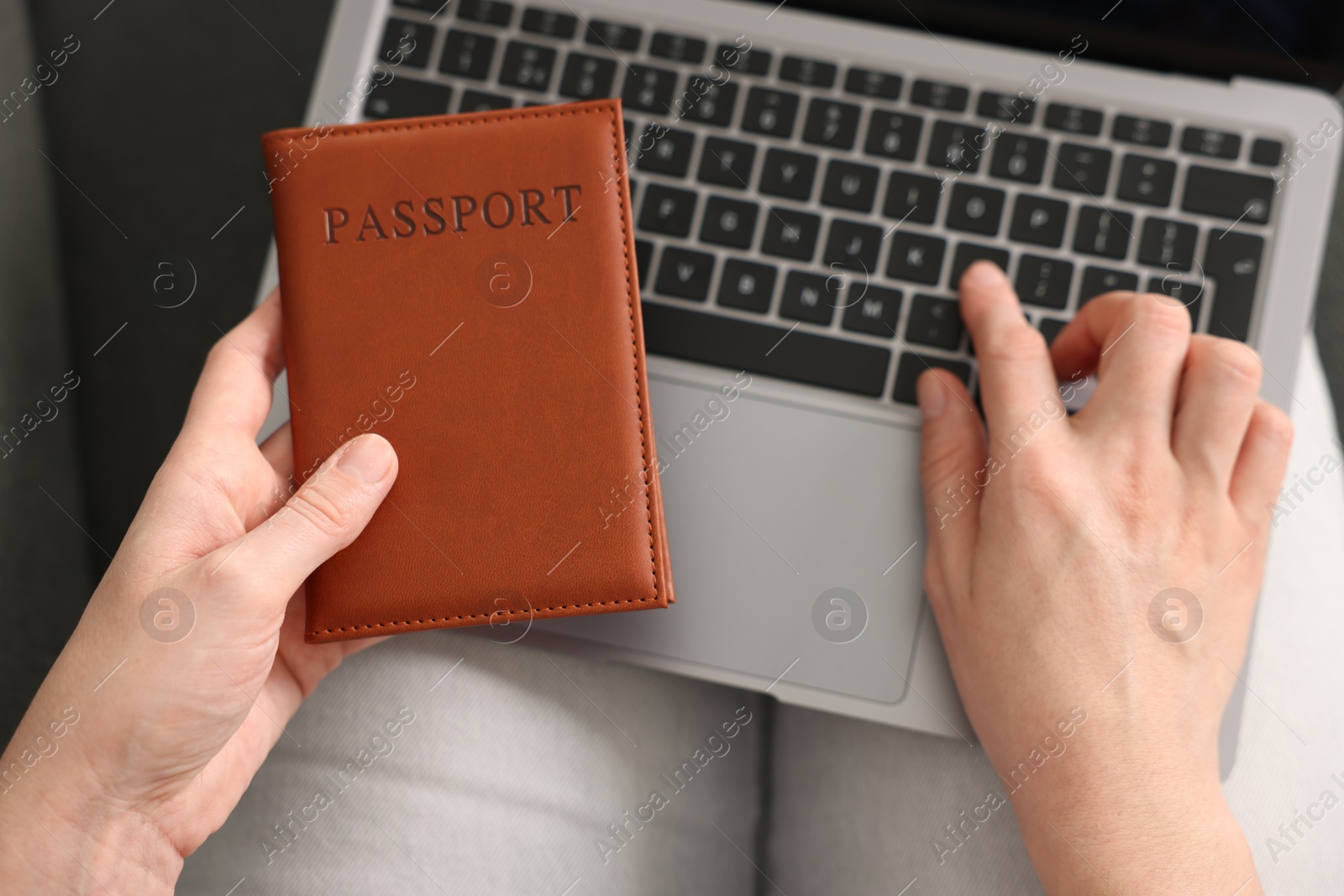 Woman with passport using laptop indoors, above view Photo of Woman with passport using laptop indoors, above view