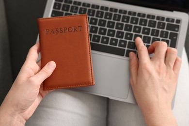 Photo of Woman with passport using laptop indoors, above view