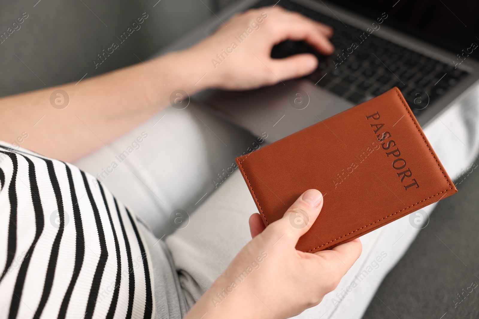 Woman with passport using laptop on sofa indoors, above view Photo of Woman with passport using laptop on sofa indoors, above view