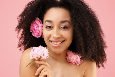 Photo of Beautiful Brazilian woman with peonies on pink background