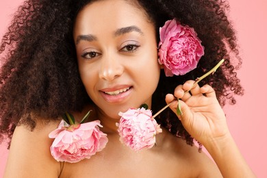 Photo of Beautiful Brazilian woman with peonies on pink background, closeup