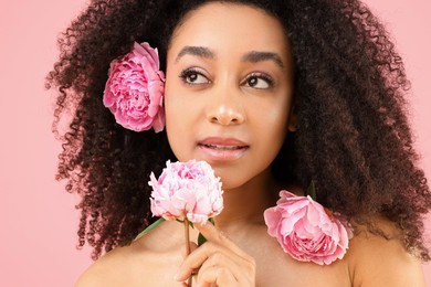 Photo of Beautiful Brazilian woman with peonies on pink background, closeup