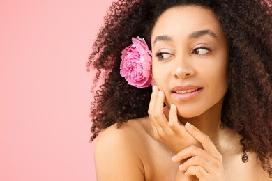 Photo of Beautiful Brazilian woman with peony flower on pink background, closeup. Space for text