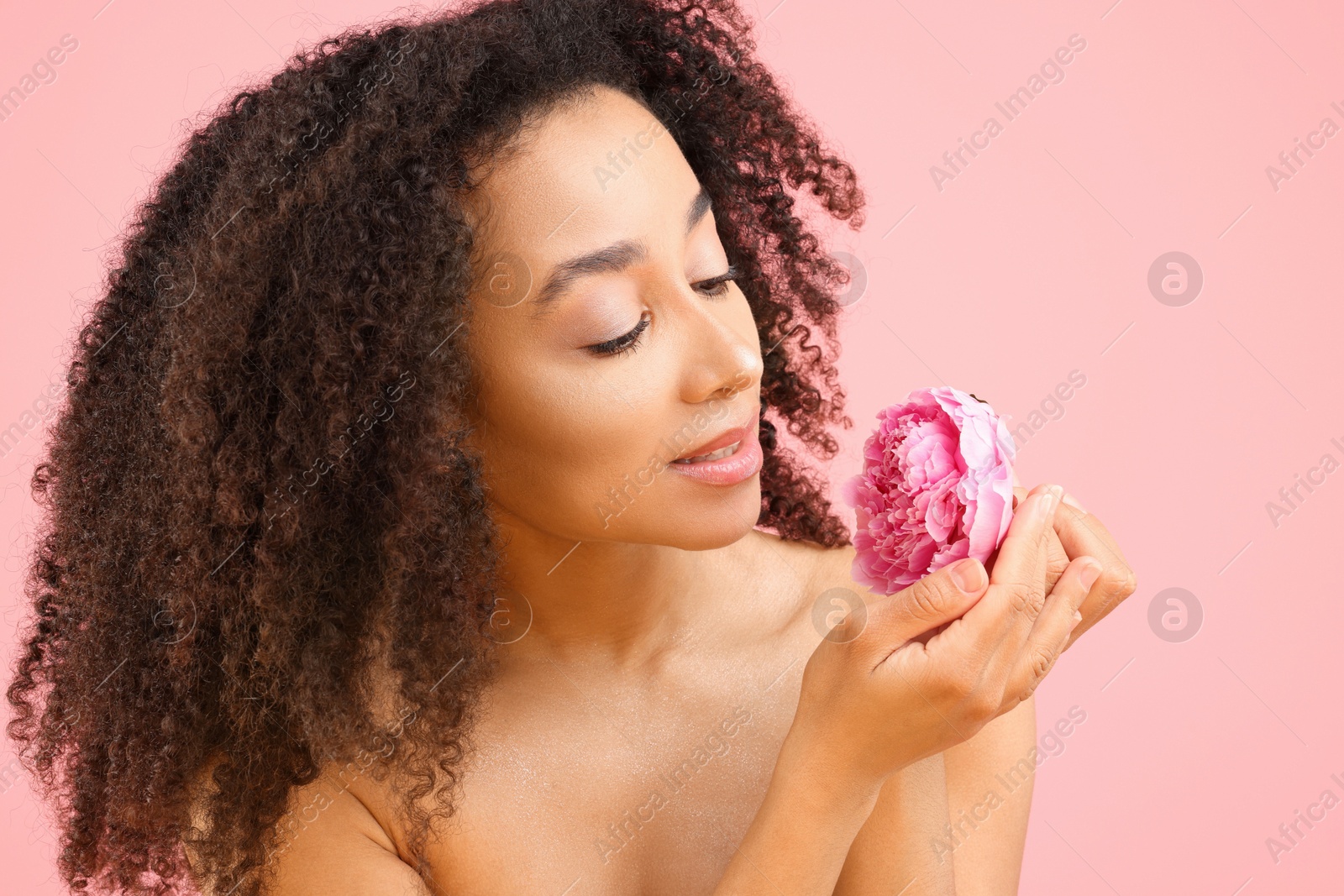 Beautiful Brazilian woman with peony flower on pink background Photo of Beautiful Brazilian woman with peony flower on pink background