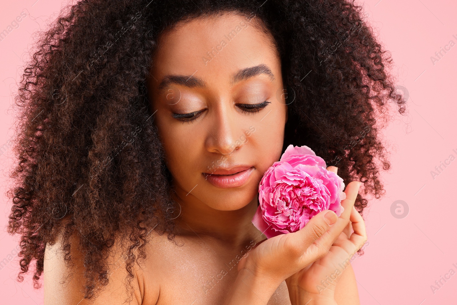 Beautiful Brazilian woman with peony flower on pink background, closeup Photo of Beautiful Brazilian woman with peony flower on pink background, closeup