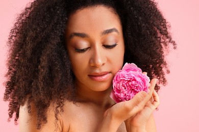 Photo of Beautiful Brazilian woman with peony flower on pink background, closeup