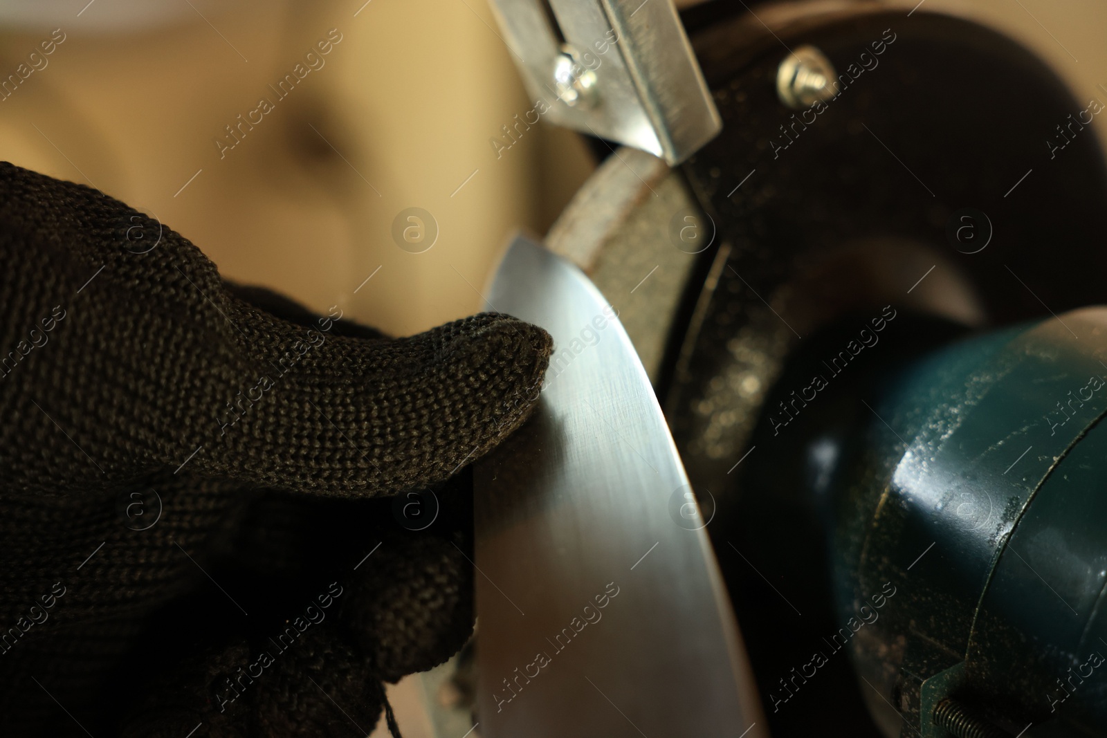 Man sharpening knife with bench grinder indoors, closeup Photo of Man sharpening knife with bench grinder indoors, closeup