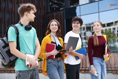 Photo of Teenagers with laptop and books near building outdoors