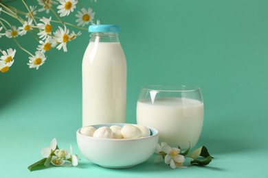 Photo of Fresh milk, mozzarella balls and flowers on turquoise background. Dairy products