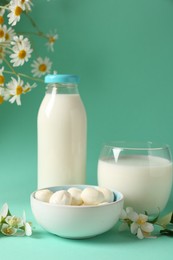 Photo of Fresh milk, mozzarella balls and flowers on turquoise background. Dairy products
