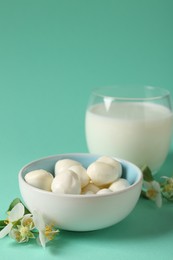 Photo of Fresh milk in glass, mozzarella balls and flowers on turquoise background, closeup. Dairy products