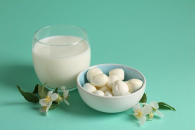 Photo of Fresh milk in glass, mozzarella balls and flowers on turquoise background. Dairy products
