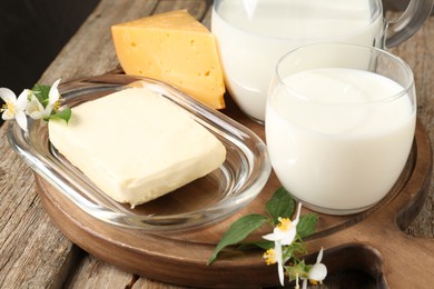 Photo of Different fresh dairy products and flowers on wooden table, closeup