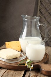 Photo of Different fresh dairy products and flowers on wooden table, closeup