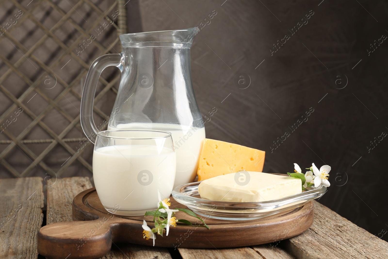 Photo of Different fresh dairy products and flowers on wooden table