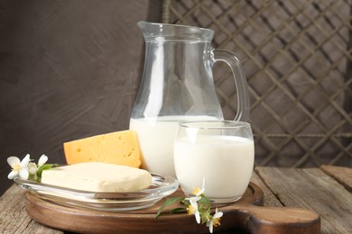 Photo of Different fresh dairy products and flowers on wooden table, closeup
