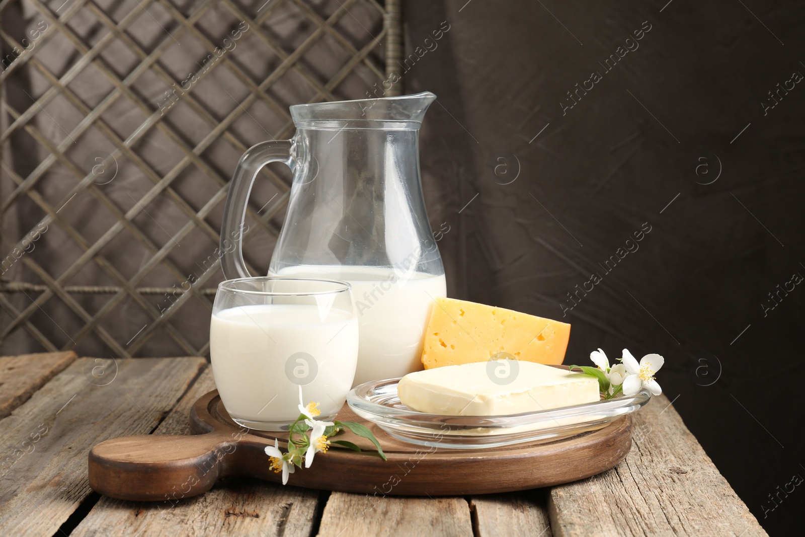 Photo of Different fresh dairy products and flowers on wooden table