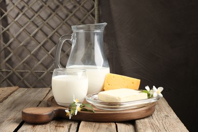 Photo of Different fresh dairy products and flowers on wooden table
