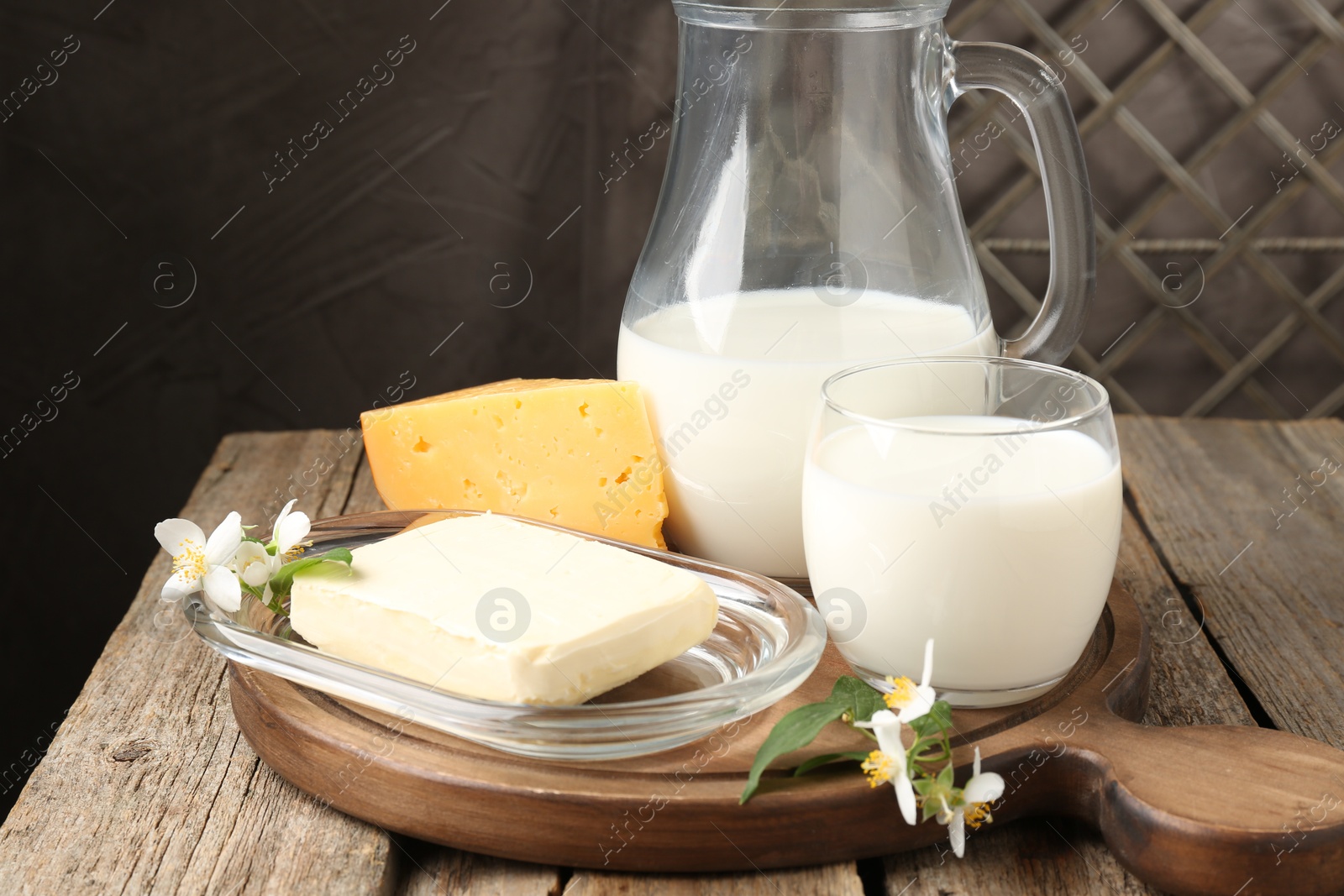 Photo of Different fresh dairy products and flowers on wooden table, closeup